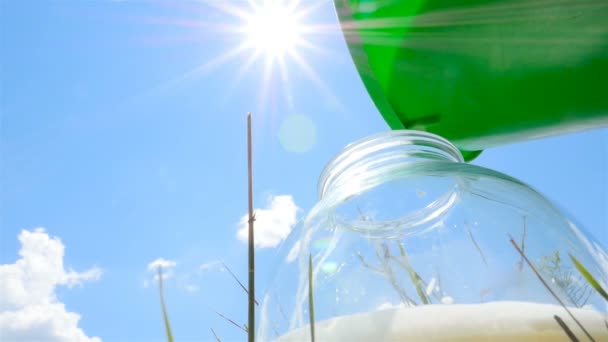 Pouring milk into a glass jar. Fresh milk. Beautiful sky and bright sun. Slow-motion . Close-up - Footage, Video