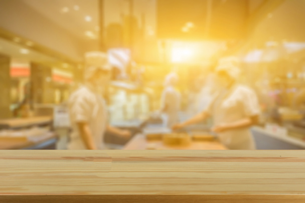 leerer brauner Holztisch im Restaurant mit verschwommenen Menschen im Hintergrund mit Bokeh-Lichtern  - Foto, Bild