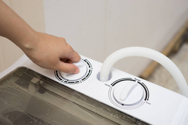 close up of female hand choosing cycle program on washing machine - Foto, imagen