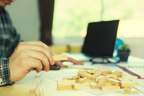 man playing wood blocks tower game at table in office - Fotoğraf, Görsel