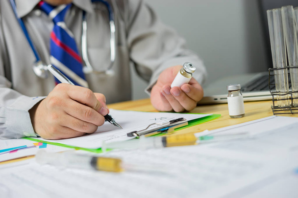 Médico escrevendo prescrição e segurando medicina no hospital
 - Foto, Imagem