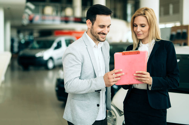 Picture of professional female salesperson working in car dealership - Foto, immagini