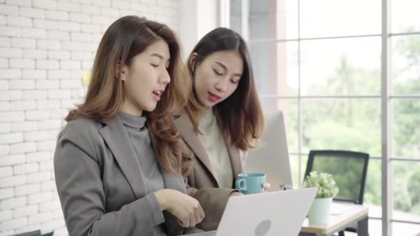 Dois asiáticos jovens empresários criativos segurando uma xícara de café, trabalhando em laptop e discuss sobre o trabalho enquanto trabalhava no escritório. Negócios casuais, trabalho freelance no café, conceito de reunião social
. - Filmagem, Vídeo