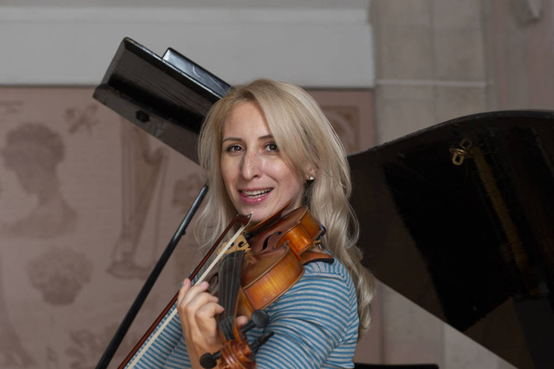Young positive blonde playing violin Portrait - Fotó, kép