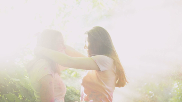 Girls enjoying pleasure pastime together spraying colorful powder and kissing - Кадри, відео