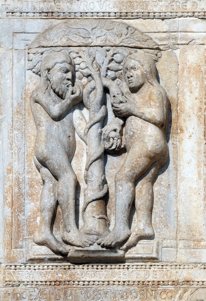 Adán y Eva comen el fruto del árbol prohibido, relieve medieval en la fachada de la Basílica de San Zenón en Verona, Italia
 - Foto, imagen