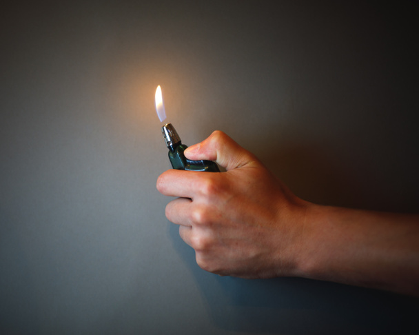 encendedor de cigarrillos encendido por una mano
 - Foto, Imagen