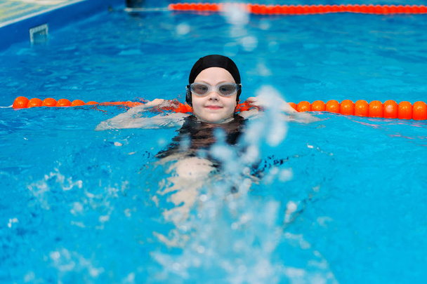 Schwimmkurse für Kinder im Pool - schönes hellhäutiges Mädchen schwimmt im Wasser - Foto, Bild