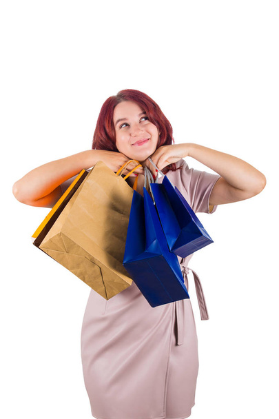 若い赤毛の女性両手の下であごの幸せ探しているキャリーのショッピング バッグと白い背景の上に孤立した瞑想. - 写真・画像