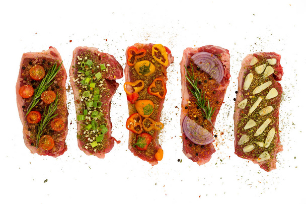 Five New York Strips deliciously seasoned in different ways with colorful vegetables isolated on white - Valokuva, kuva