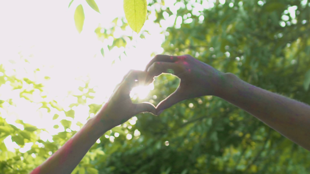 Para zakochanych, przeplot palce w postaci serca, próbując złapać słońca romantyczny - Materiał filmowy, wideo