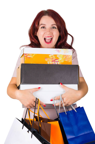 Encantada joven mujer adicta a las compras sosteniendo cajas de compras y bolsas de papel con regalos buscados para las vacaciones, boca sorprendida abierta aislada sobre fondo blanco
. - Foto, imagen