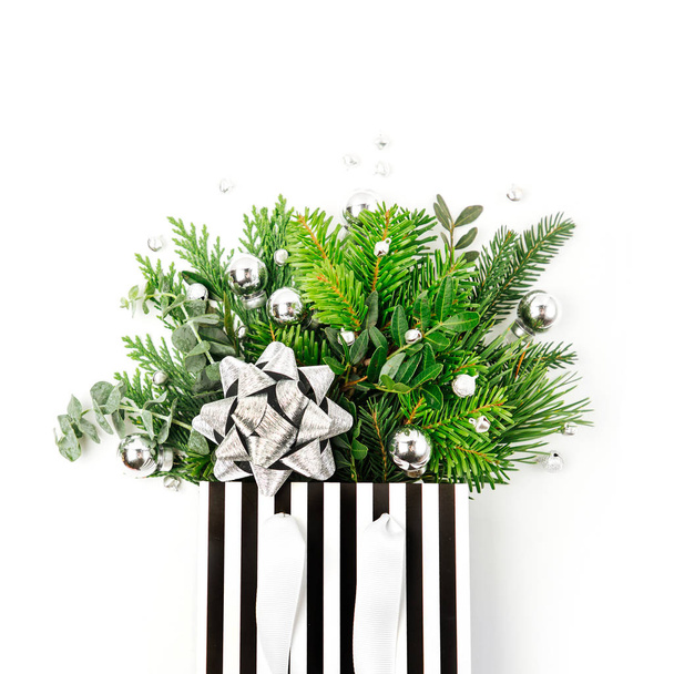 Shiny Christmas decorations and fir branches in a shopping bag on a white background. Christmas Shopping concept. Flat lay, top view - Valokuva, kuva