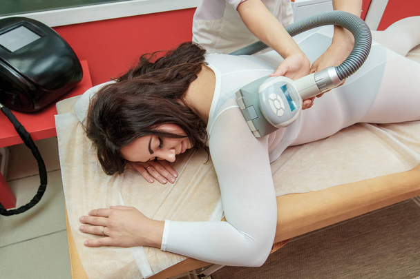 Woman having procedure of anti cellulite lpg treatment massage with therapist and apparatus in cosmetology clinic - Foto, Bild