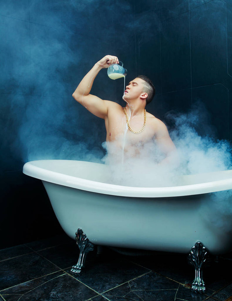 attractive muscular young man taking a bath with milk - Valokuva, kuva