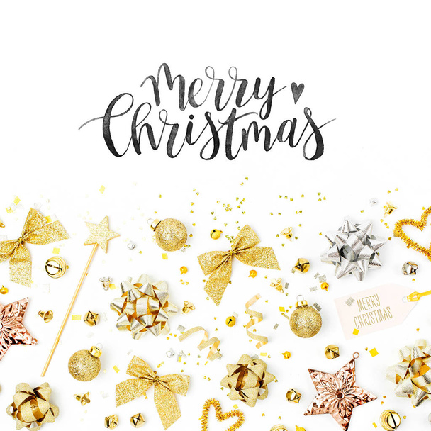 Christmas decorations in gold colors with merry christmas lettering on white background - 写真・画像
