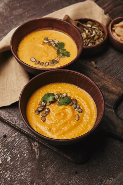 close-up view of delicious pumpkin soup with seeds in bowls on wooden table  - Photo, Image