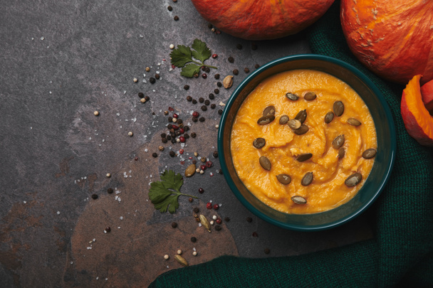 top view of bowl with delicious pumpkin soup and fresh pumpkins on dark surface - Photo, Image