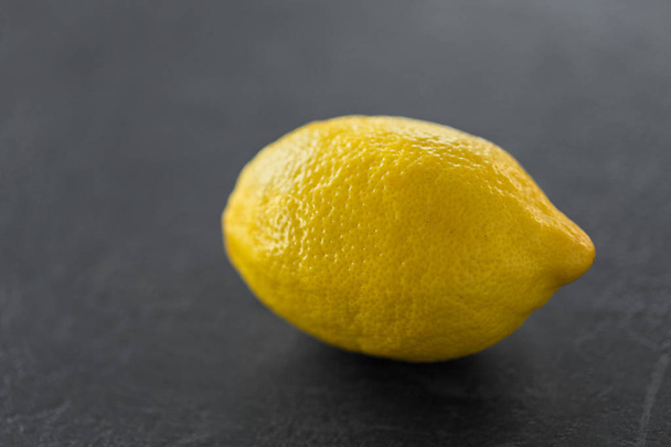 close up of whole lemon on slate table top - Foto, afbeelding