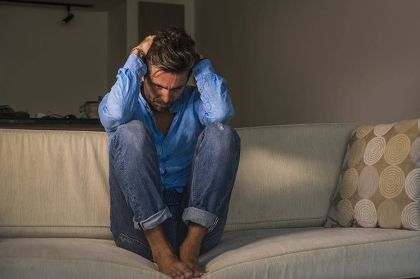lifestyle portrait of young attractive and handsome sad latin man sitting tired and depressed at home sofa couch feeling overwhelmed and worried suffering depression crisis and anxiety problem - Φωτογραφία, εικόνα