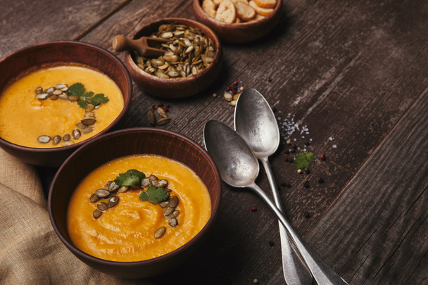 delicious pumpkin soup in bowls and spoons on wooden table  - Foto, afbeelding