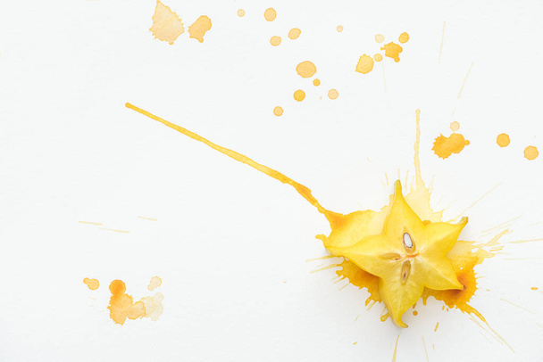 top view of exotic star fruit on white surface with yellow paint splashes - Photo, Image