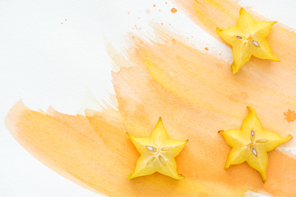 vista elevada de sabrosos frutos de la estrella en la superficie blanca con acuarela naranja
 - Foto, Imagen