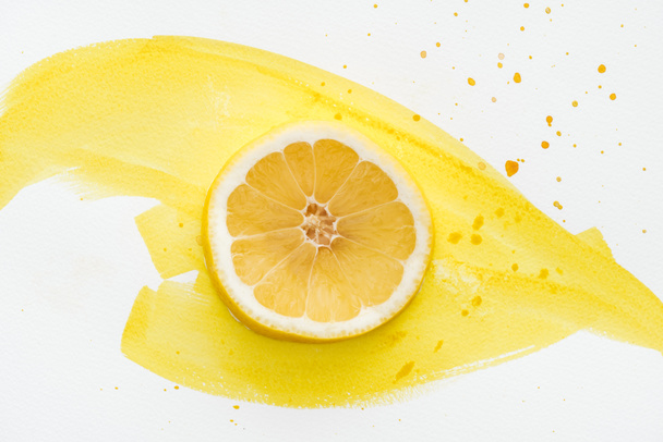 top view of lemon piece on white surface with yellow watercolor - Photo, Image