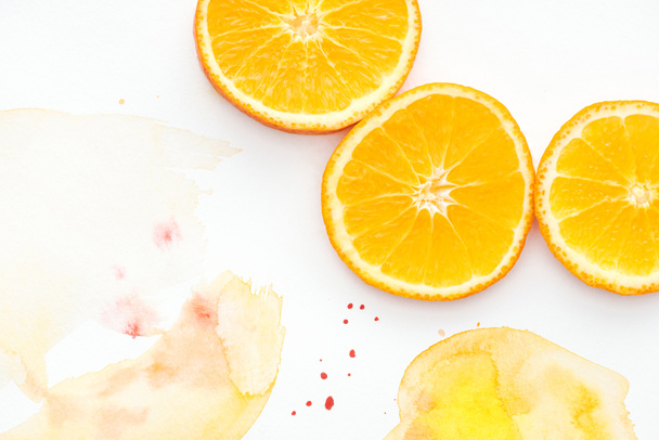 top view of citrus pieces on white surface with yellow watercolor - Foto, Imagem