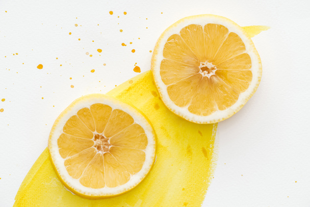 top view of citrus pieces on white surface with yellow watercolor - Fotoğraf, Görsel
