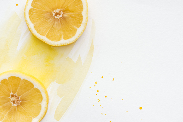 top view of yummy lemon pieces on white surface with yellow watercolor - Photo, Image