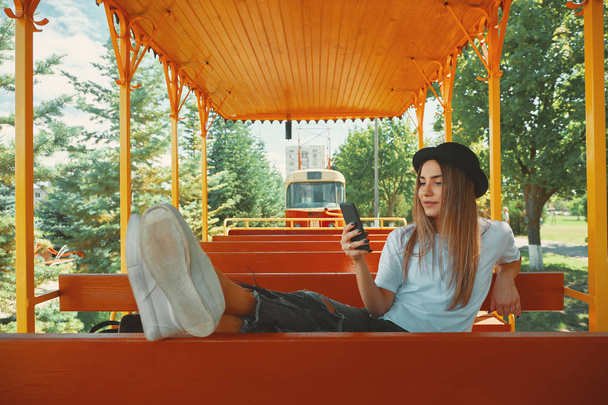 ein attraktives Mädchen in ihren Zwanzigern macht Fotos für ihren Blog, während sie mit einer Straßenbahn im Hintergrund eine Stadtrundfahrt unternimmt. Mädchen macht Selfie. - Foto, Bild