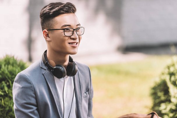 komea hymyilevä aasialainen mies kuulokkeet katselee pois
 - Valokuva, kuva