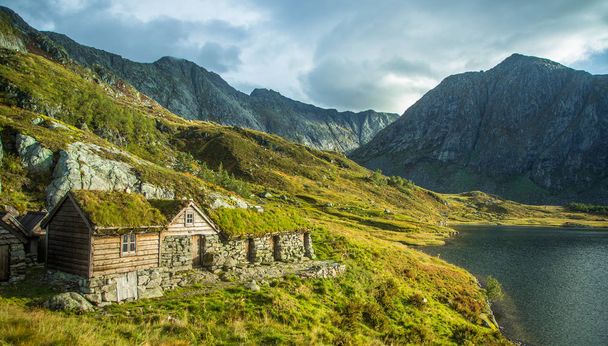 Μια όμορφη, ιστορική παλιά πέτρινα κτίσματα στα βουνά του εθνικού πάρκου Folgefonna στη Νορβηγία. Παλιά σπίτια με στέγες χόρτο κοντά στη λίμνη. Φθινοπωρινό τοπίο. - Φωτογραφία, εικόνα