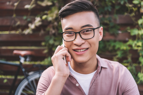 ritratto di sorridente asiatico uomo in occhiali parlando su smartphone
 - Foto, immagini