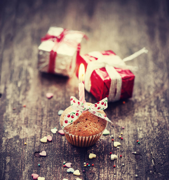 closeup view of cupcake with candle and colorful christmas decorations in vintage style over wooden background - Valokuva, kuva