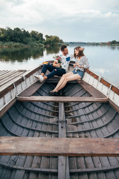 Lovely couple relaxing in boat on water with sweet fruits. Dating concept. - Valokuva, kuva