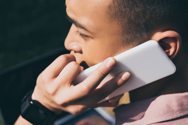 vista lateral de asiático hombre hablando en smartphone
 - Foto, imagen