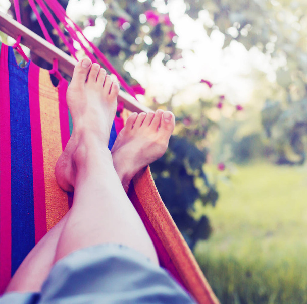 female legs laying in hammock in green garden  - Zdjęcie, obraz