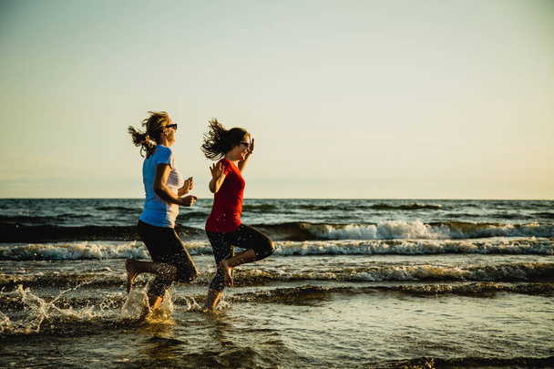 Active teenage girl and woman jogging together at sea - Foto, Imagen