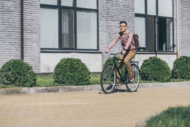  asiático jovem homem com mochila andar de bicicleta na rua
 - Foto, Imagem