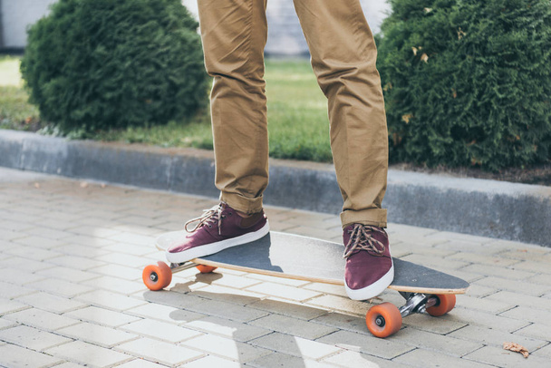 cropped shot of man standing on longboard on street - Photo, Image
