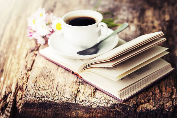 closeup view of coffee cup with flowers and book on wooden table - Fotó, kép