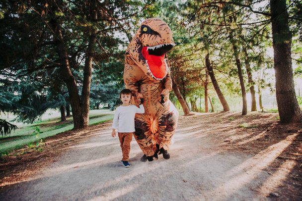 Father and son playing at the park, with a dinosaur costume, having fun with the family outdoor - Valokuva, kuva