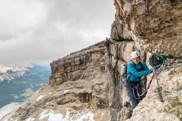 alpinistas em uma íngreme Via Ferrata com vista para as Dolomitas italianas
 - Foto, Imagem