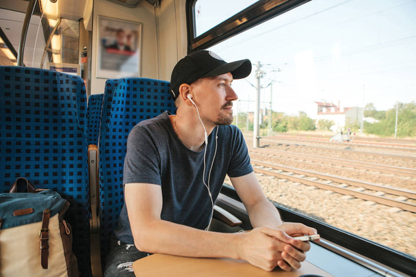 Genç bir adam bir müzik veya podcast bir tren seyahat ederken dinler - Fotoğraf, Görsel