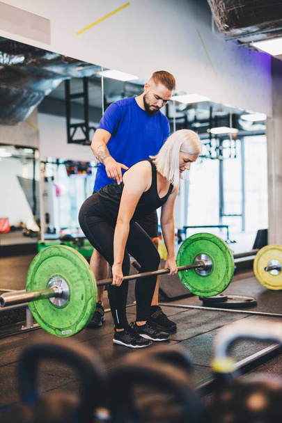Personal trainer assisting woman lifting weights. Fitness club. Sporty lifestyle. - Fotó, kép