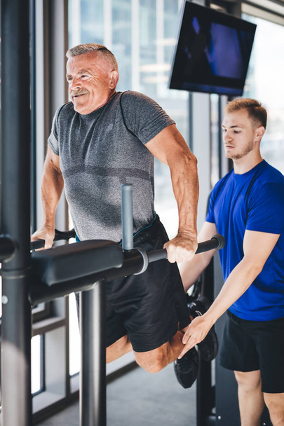 Gym instructor helping senior man at the gym. Sport and physical training. - Photo, Image