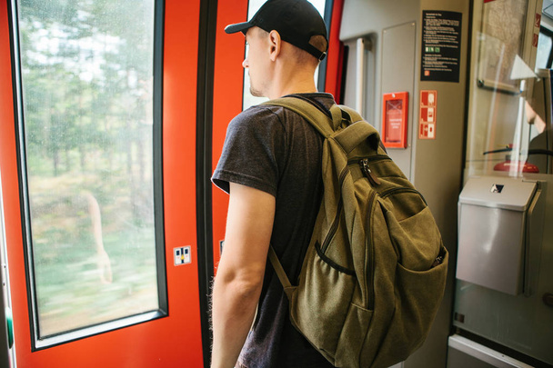Turista o studente con uno zaino in attesa che il treno si fermi
 - Foto, immagini