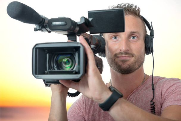 smiling man with professional camcorder and headphones - Photo, Image